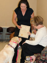 Laura presenting certified therapy dog with certificate.